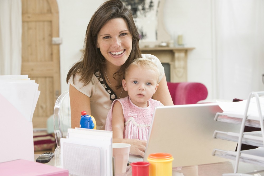 Mãe com bebê e computador demonstrando que é possível conciliar vida pessoal e profissional.